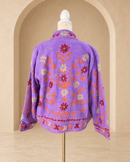 Vista posterior de blazer violeta con bordado floral en espalda y mangas.